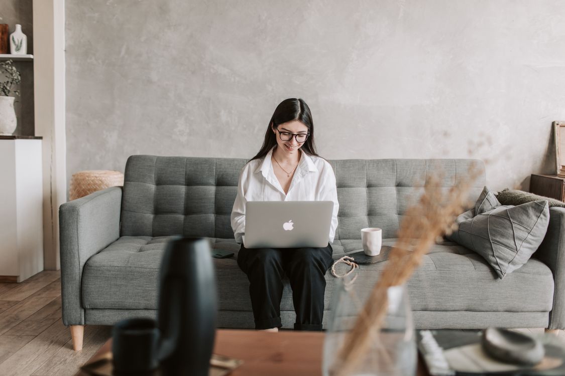 Remote worker smiling while using a laptop in a comfortable home setting