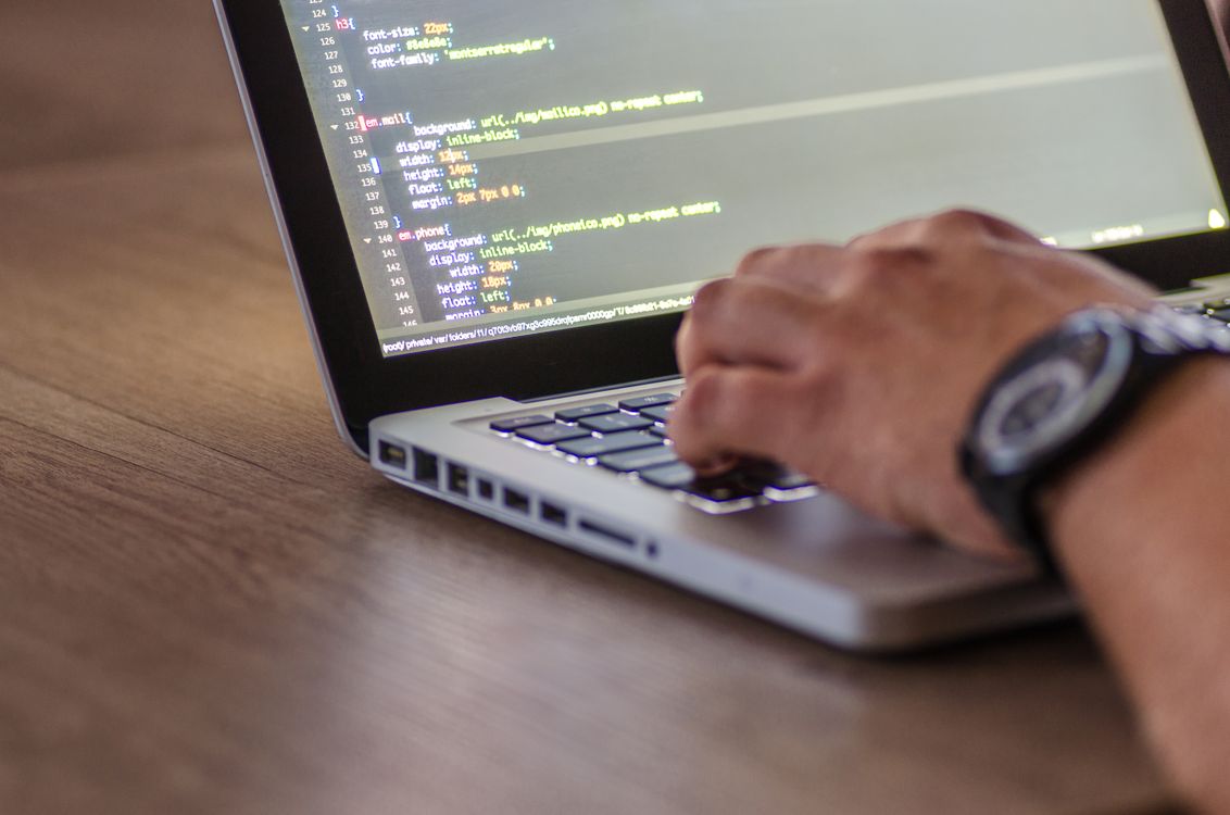 Close-up of hands typing on a laptop keyboard while coding