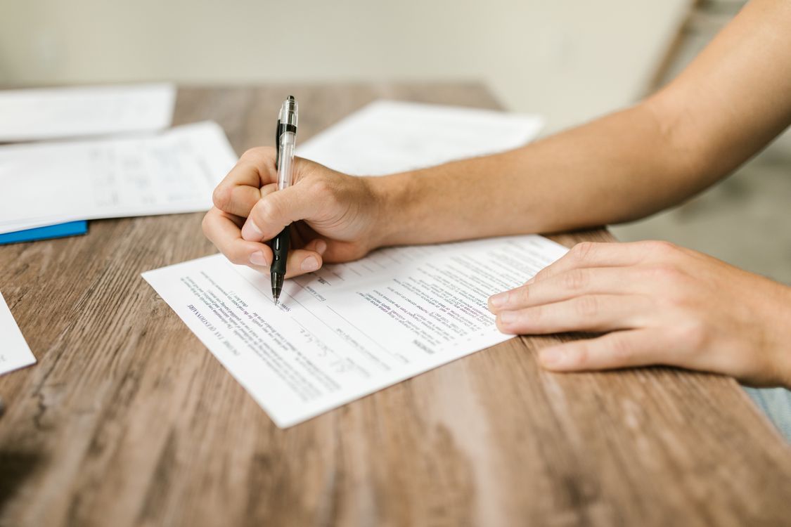 Hand filling out a government job application form with a pen