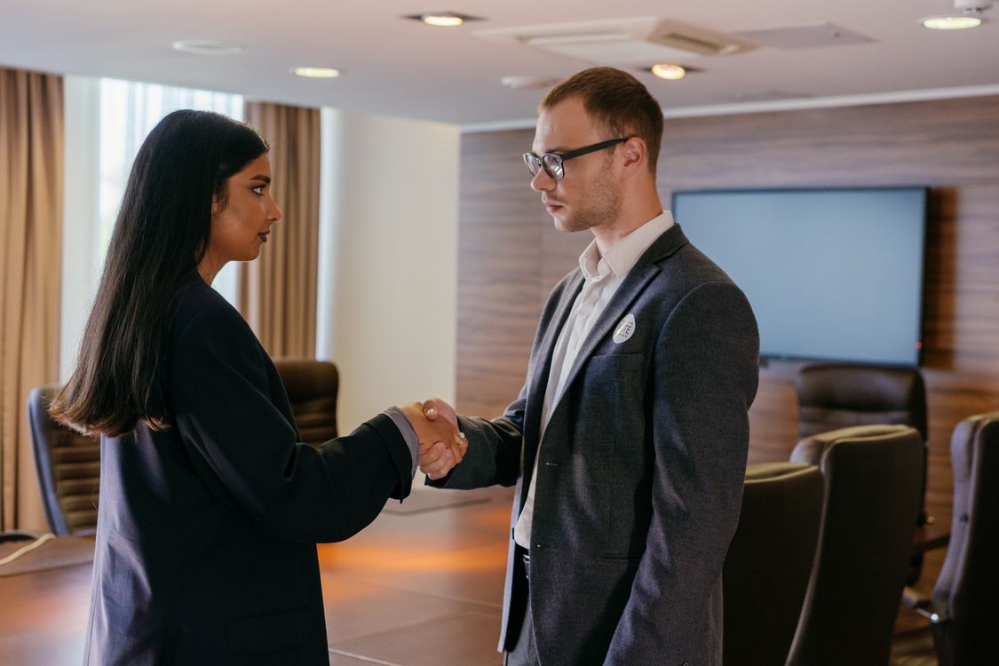 Two professionals shaking hands in a conference room, representing career advancement after certification