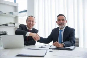 Two businessmen shaking hands after signing a contract, representing a successful job offer negotiation