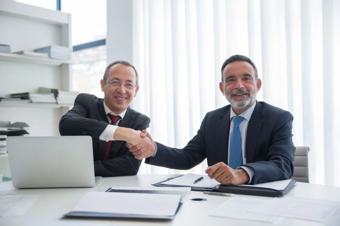 Two businessmen shaking hands after signing a contract, representing a successful job offer negotiation
